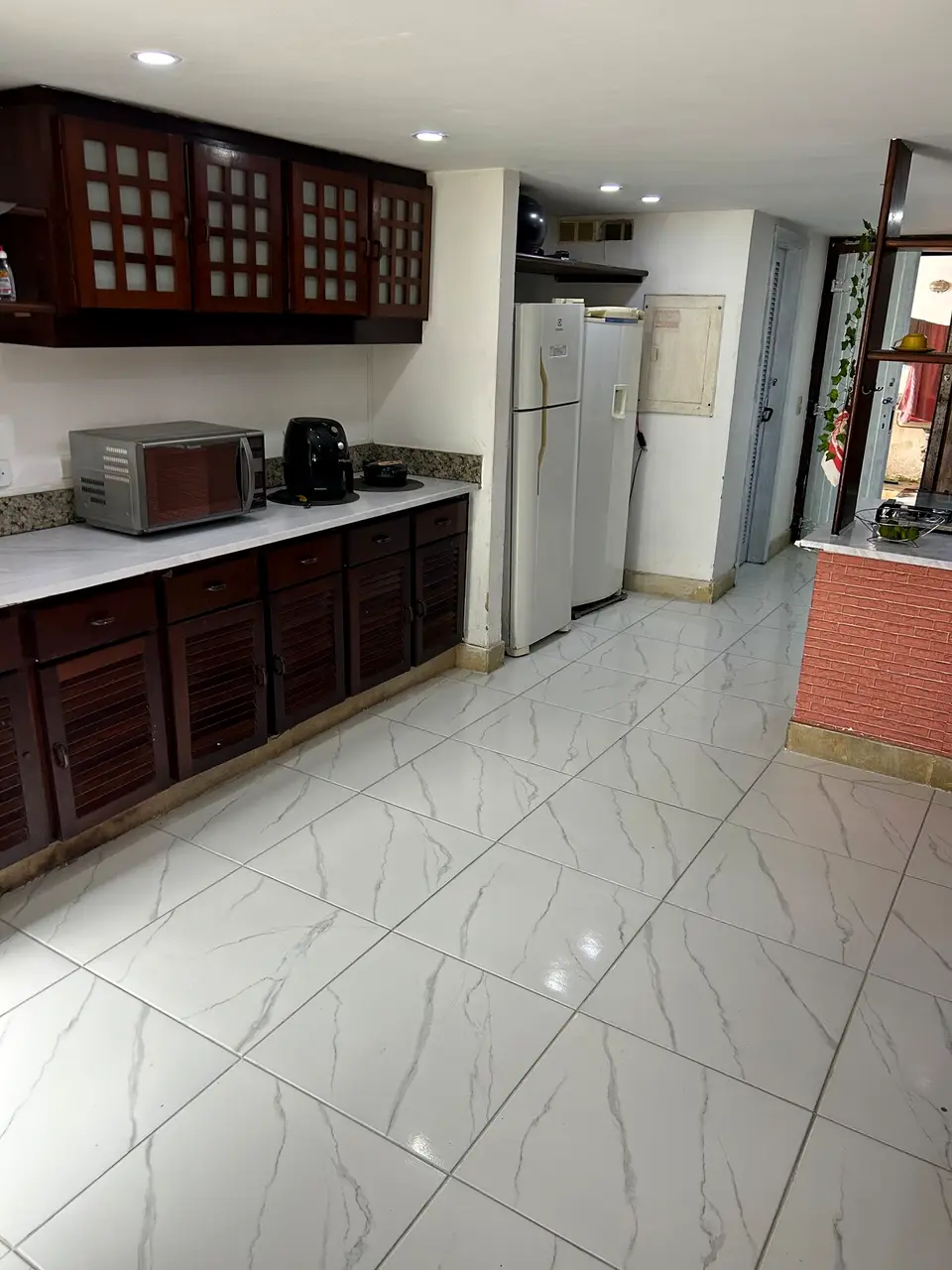 Cozinha completa com armários planejados, geladeira e micro-ondas