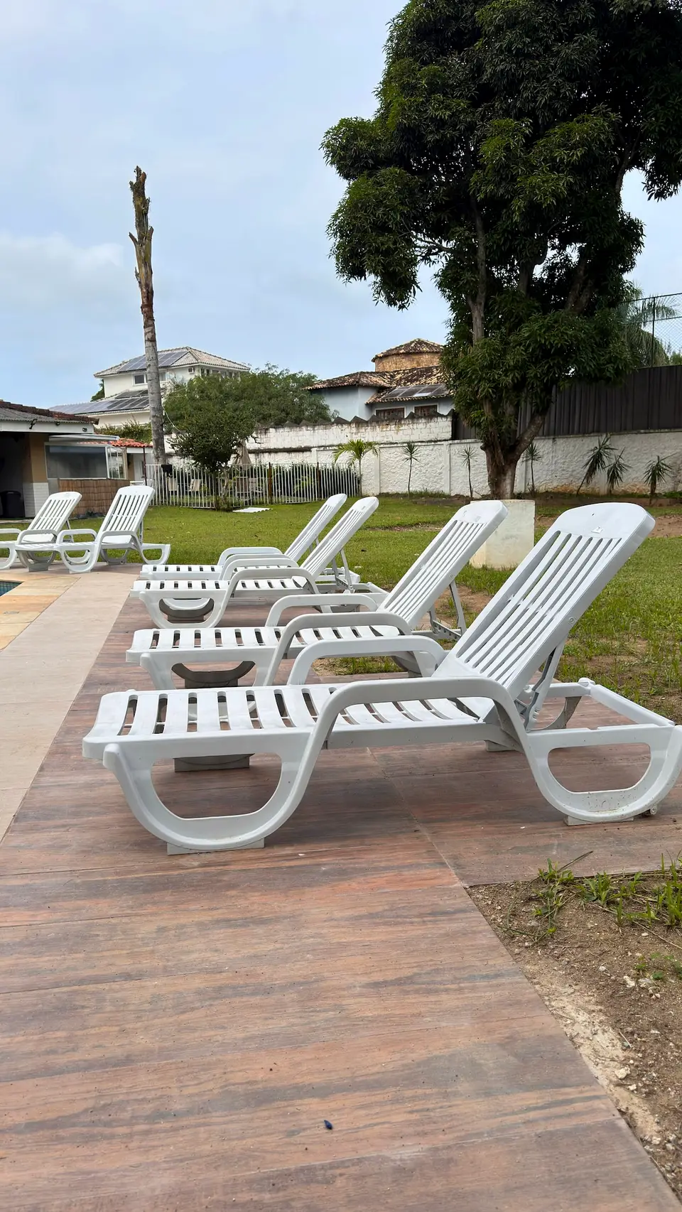 Deck de madeira e jardim da propriedade, com casas do entorno ao fundo