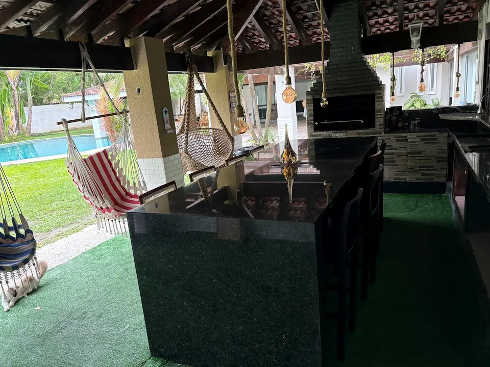 Espaço gourmet coberto com churrasqueira de alvenaria, bancada e vista para a piscina