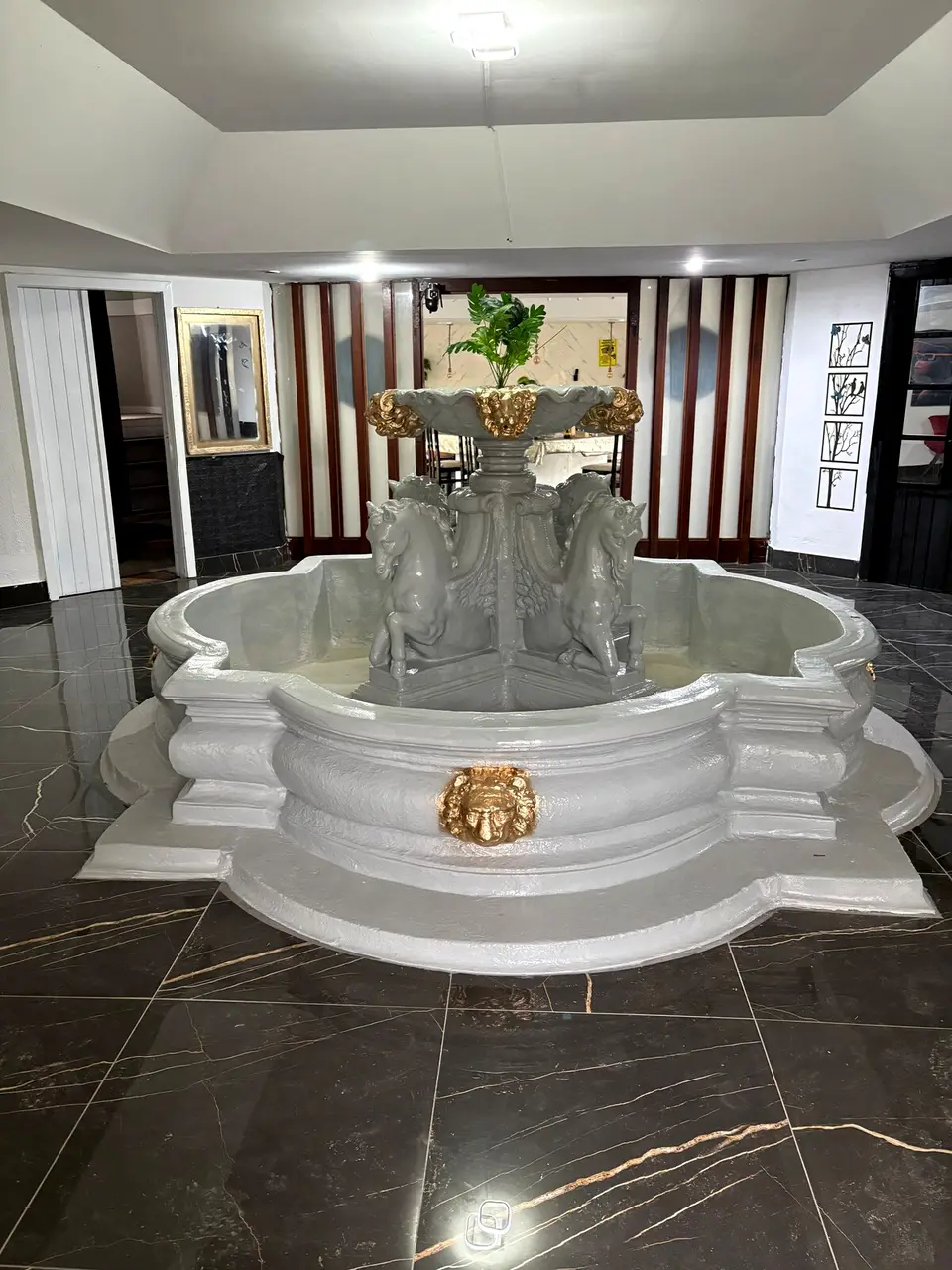 Hall de entrada com piso de mármore preto veiado de dourado e chafariz ornamental