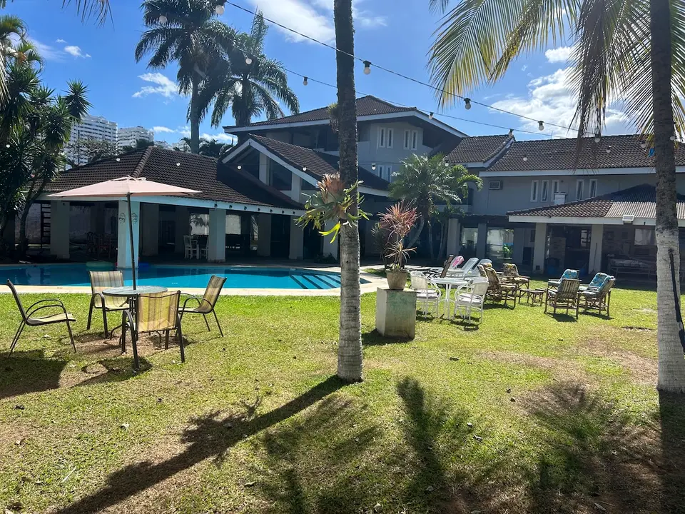 Jardim com piscina, varal de luzes e área de estar externa, em dia de céu azul