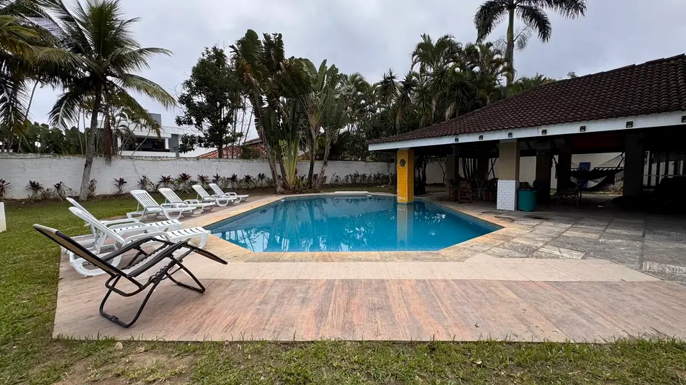 Piscina com deck de pedra e espreguiçadeiras, em dia claro