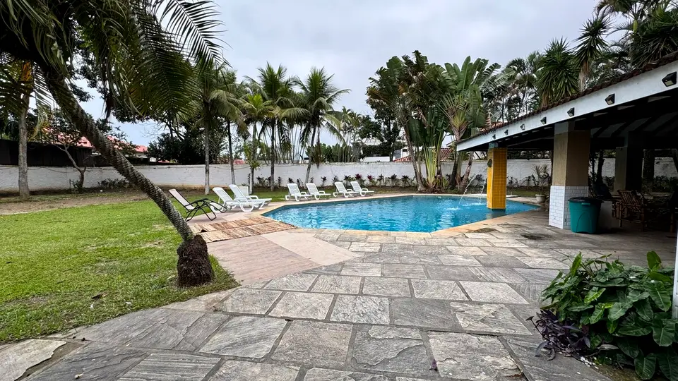 Fileira de espreguiçadeiras junto à piscina, com o jardim ao fundo