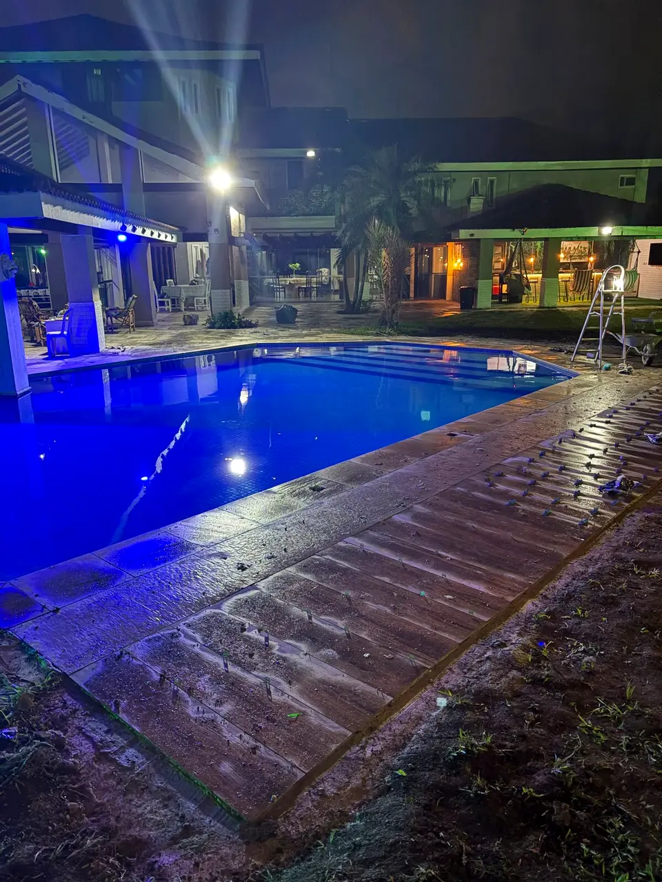 Piscina iluminada à noite, com luz azul refletindo na água
