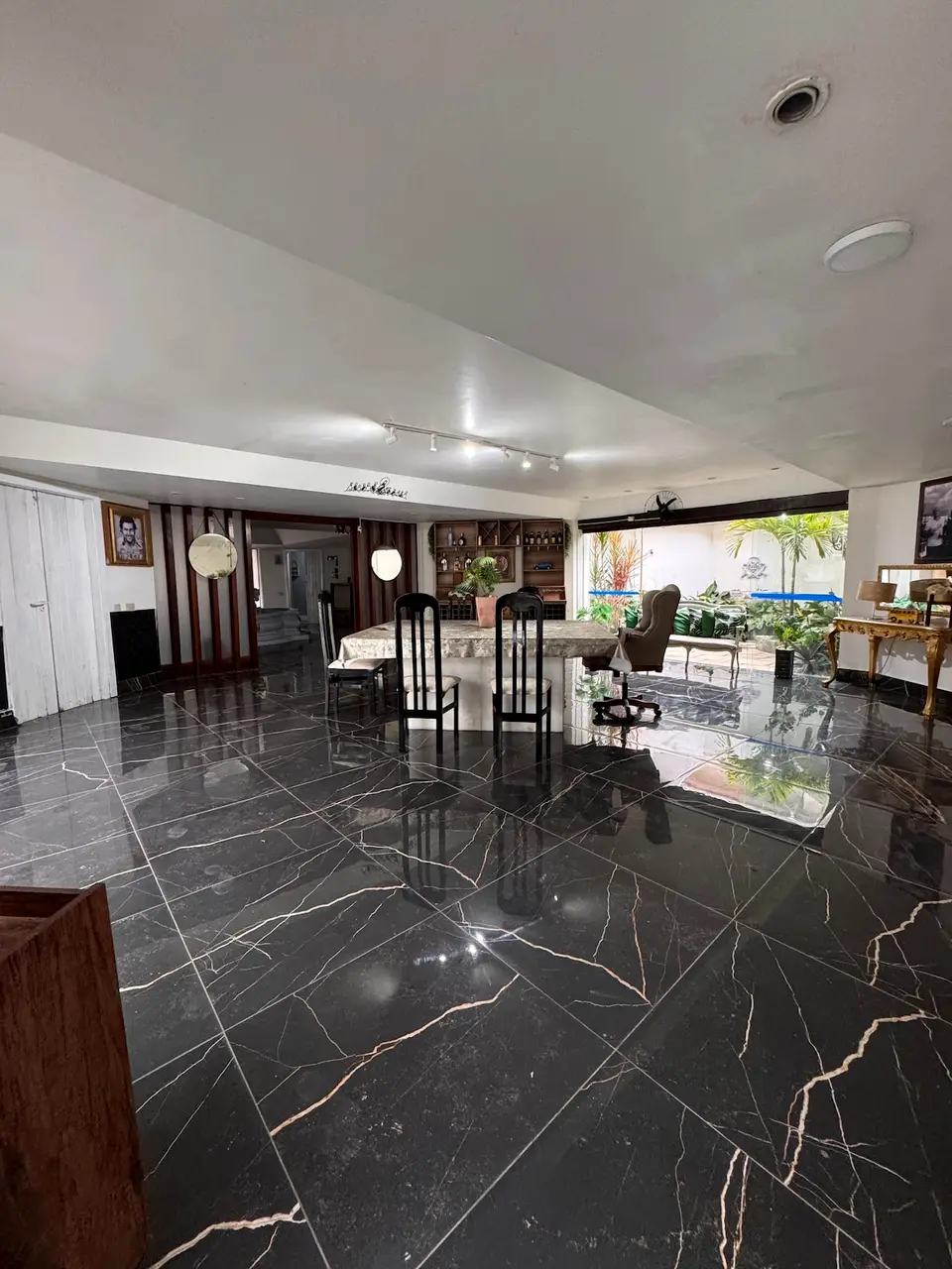 Sala de jantar com piso de mármore escuro e aparador dourado
