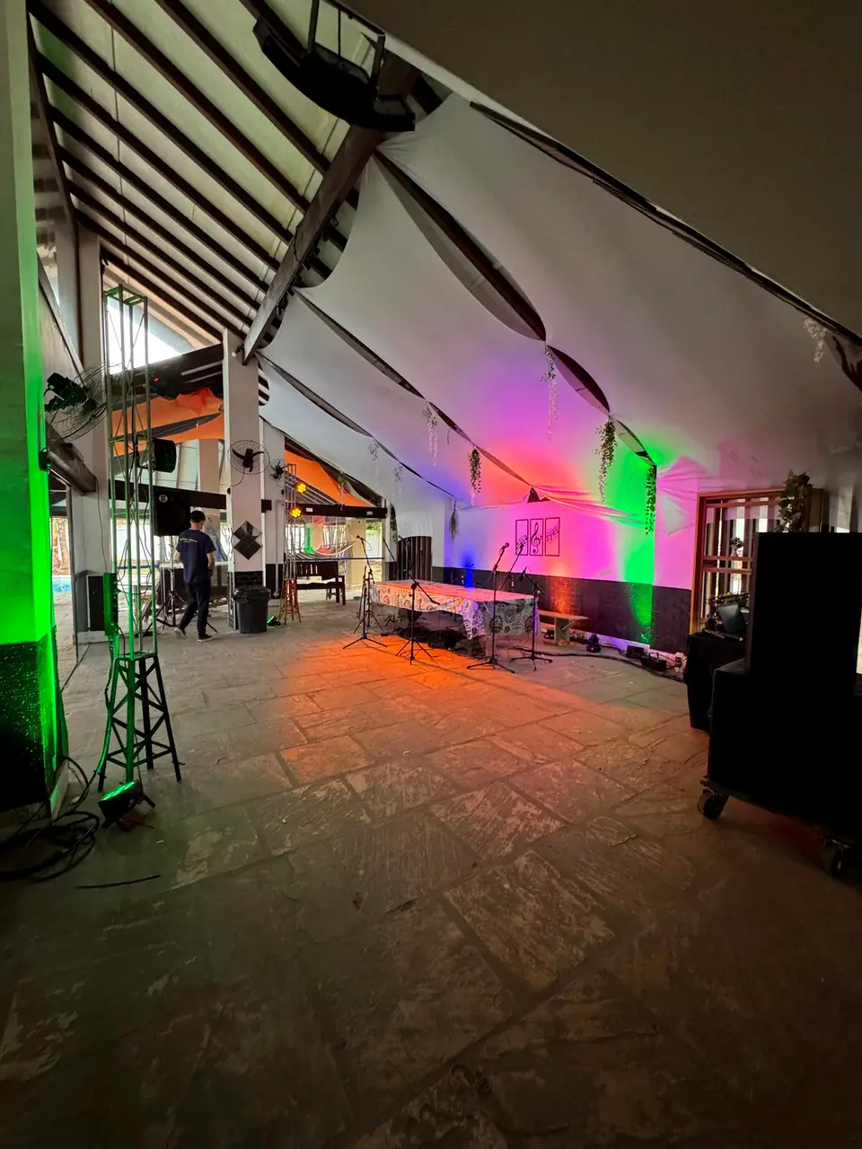 Salão de eventos montado com iluminação cênica colorida e equipamento de som