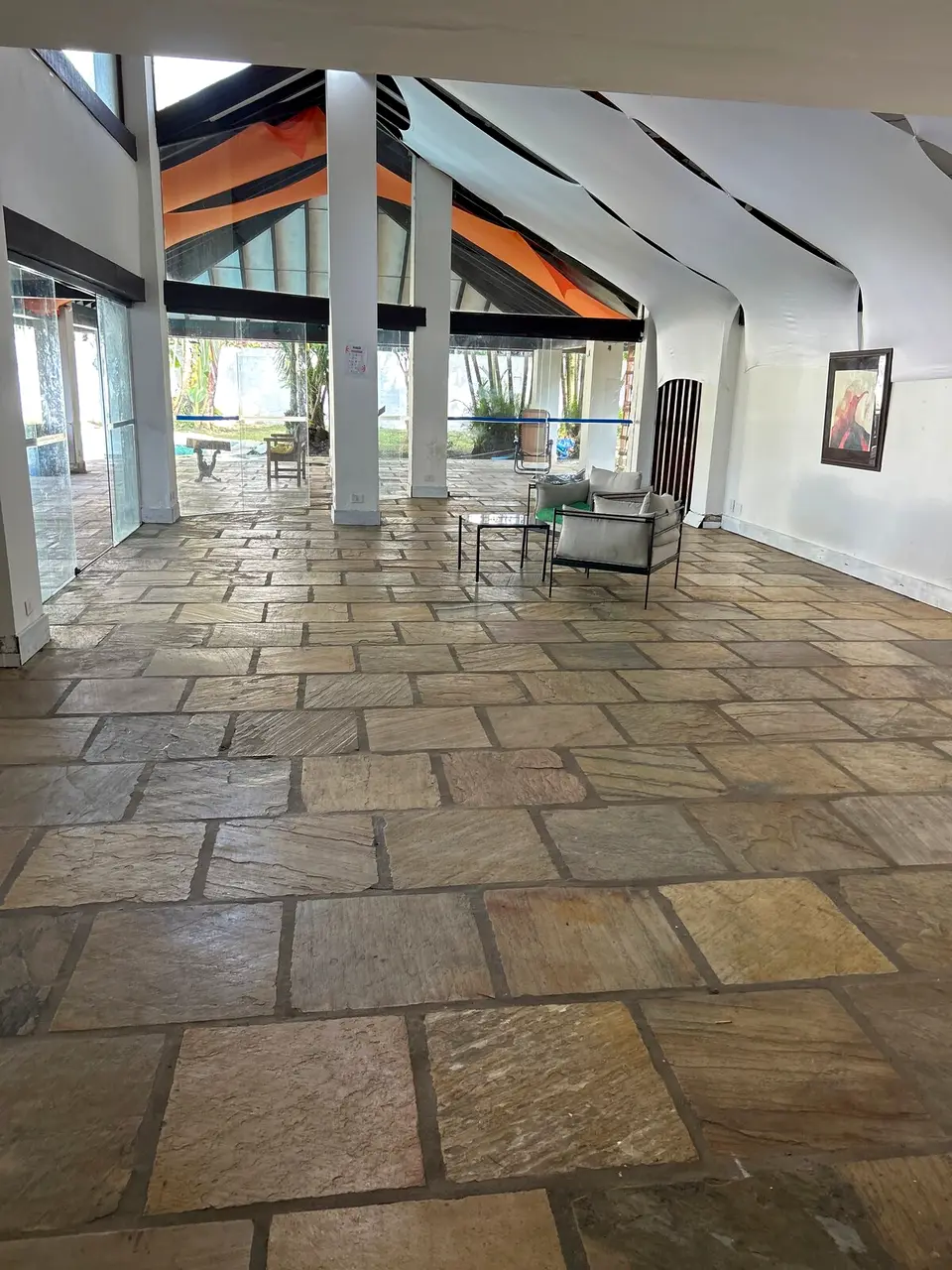 Salão coberto com piso de pedra e teto tensionado, preparado para receber eventos