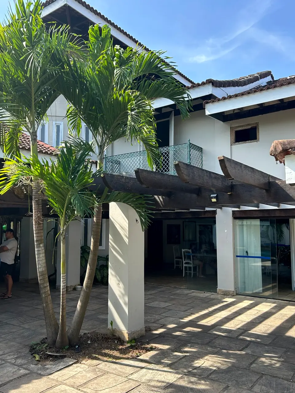 Detalhe da varanda com guarda-corpo em ferro trabalhado, emoldurada por folhagem