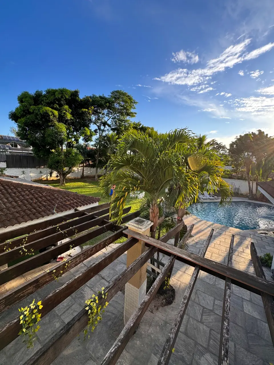 Vista da varanda superior para o jardim e a piscina ao entardecer